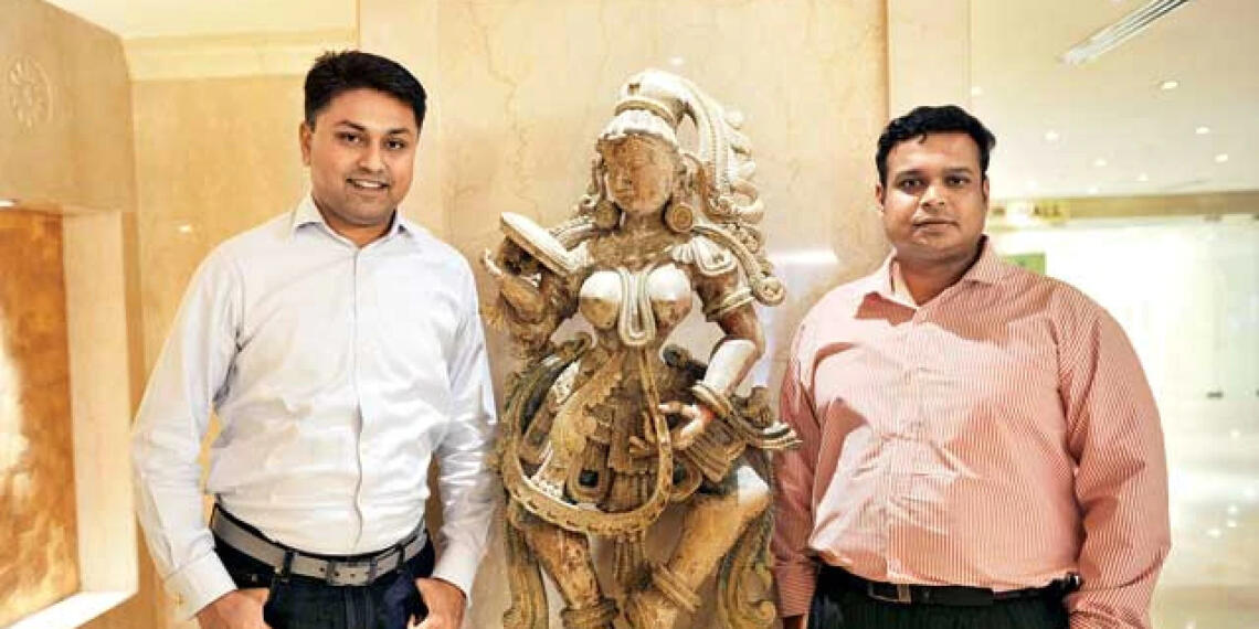 विजय कुमार प्राचीन मूर्ति के साथ खड़े है