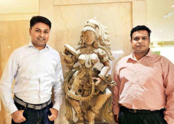 विजय कुमार प्राचीन मूर्ति के साथ खड़े है